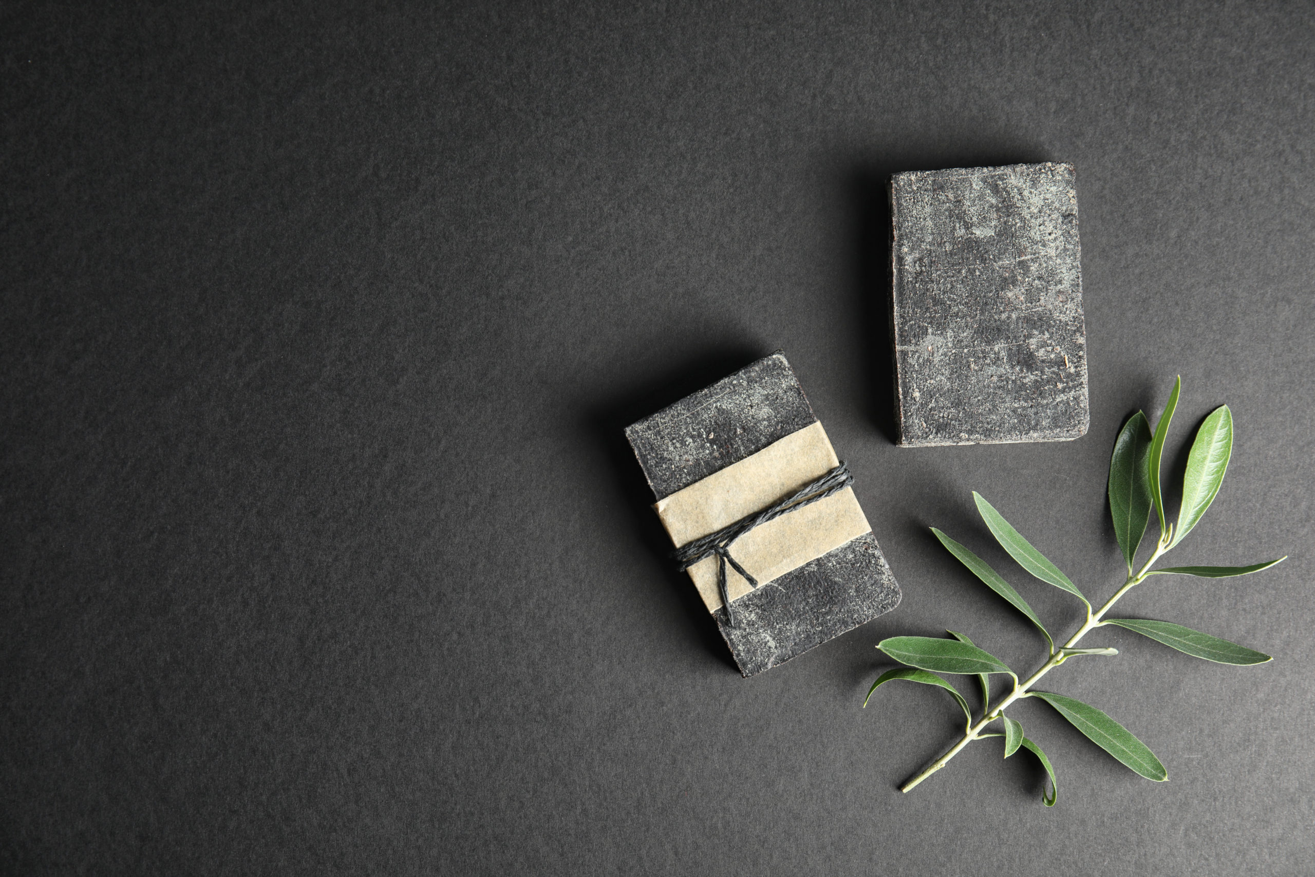 Handmade soap bars with olive twig and space for text on black b